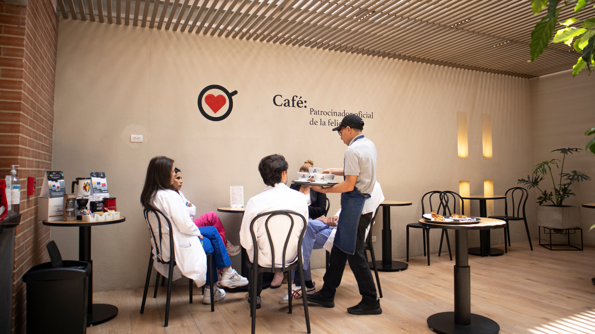 Barista sirviendo café de especialidad Amor Perfecto a clientes en nuestra tienda de Bogotá, bajo el lema Patrocinador oficial de la felicidad.