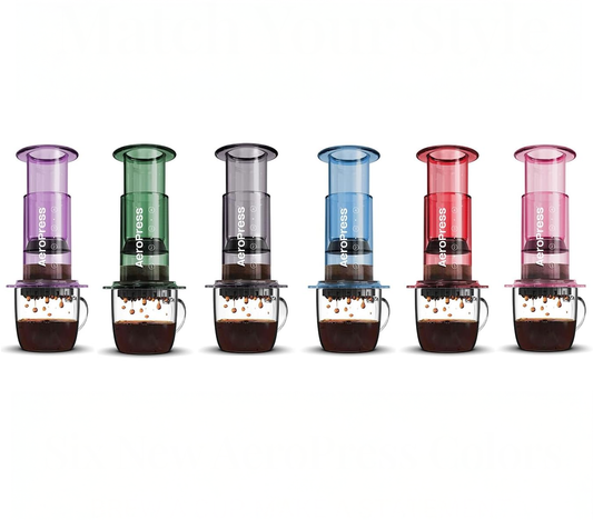 Colección de cafeteras AeroPress Clear en colores translúcidos: morado, verde, gris, azul, rojo y rosado. Cafetera manual portátil para preparar café de especialidad con diseño moderno.