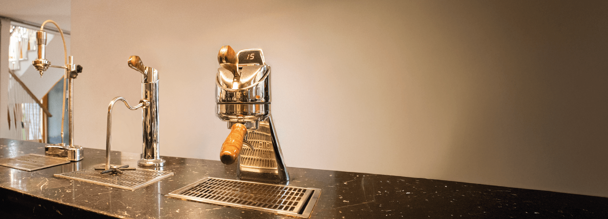 Barra de café minimalista con sistema Modbar integrado en mostrador de mármol negro. Módulos profesionales de espresso, vapor y filtrado de La Marzocco distribuidos por Amor Perfecto.